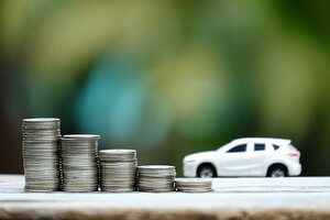 Sälja bildelar Leksaksbil vid sidan av staplade mynt